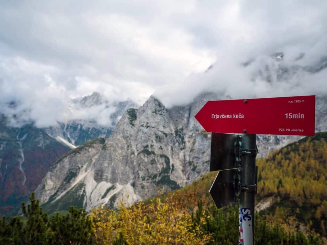 Remoto paisaje de montaña con picos rocosos envueltos en niebla y árboles otoñales en el refugio de Erjavčeva.